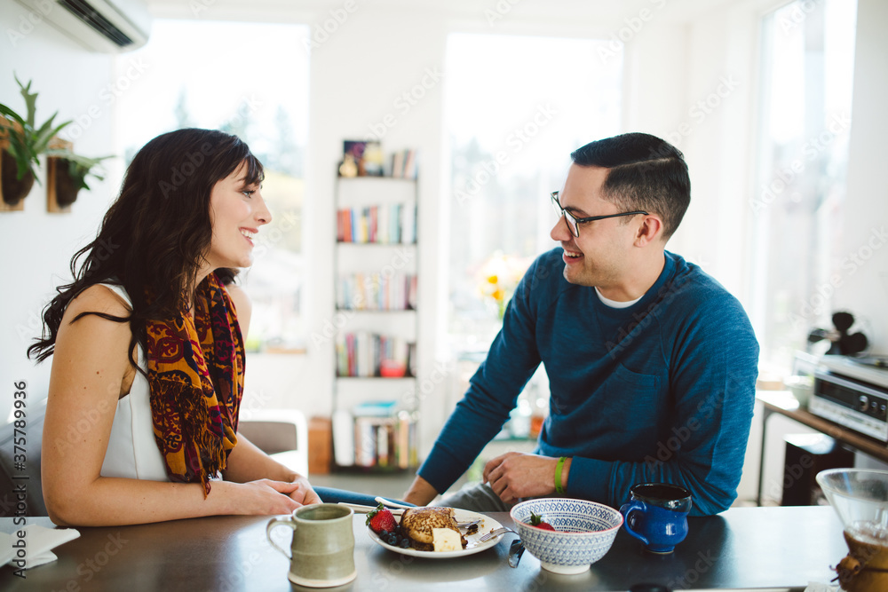 Young good looking couple eat breakfast together at their kitchen bar