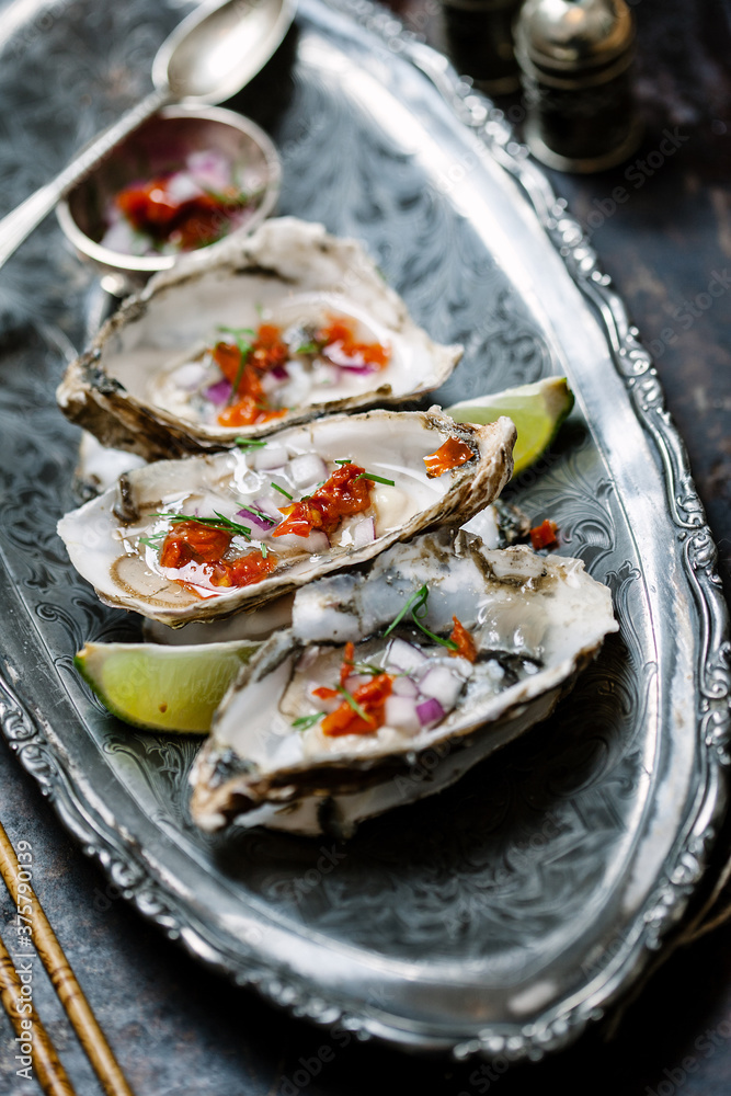 Tray of oysters with garnish ready to eat. Selective focus, side view. Tray of oysters with garnish ready to eat. Selective focus, side view.
