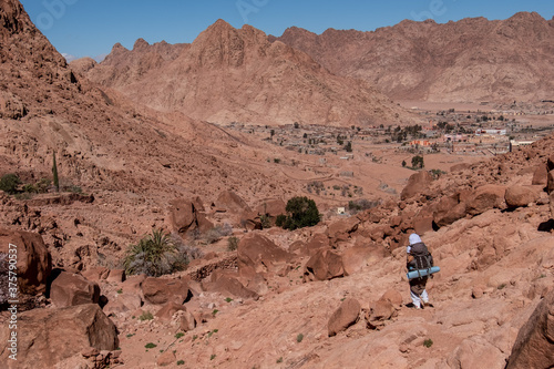 A local bedouin on its way to the city Saint Catherine, Southern Sinai, Egypt. Panoramic view on surrounding red mountains, rock walls and huge boulders of amazing forms.