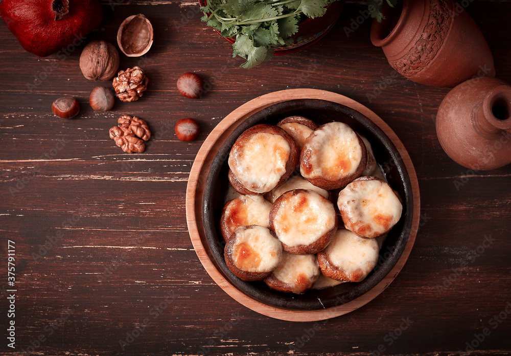 mushrooms baked with suluguni cheese on ketsi , a traditional Georgian dish , horizontal, no people mushrooms baked with suluguni cheese on ketsi , a traditional Georgian dish , horizontal, no people
