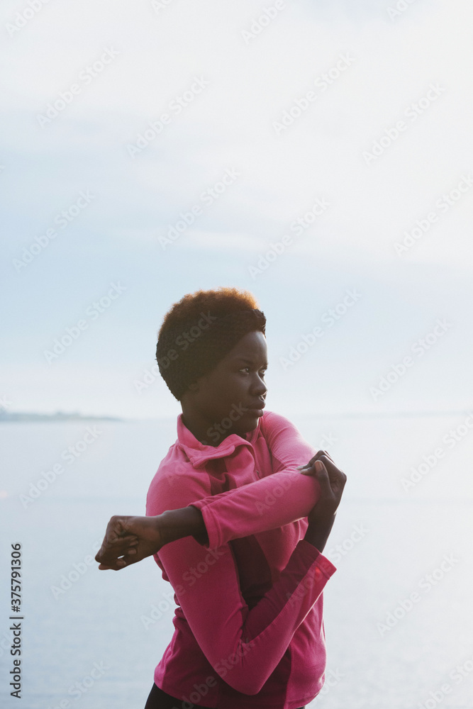Young african woman stretching and preparing for running workout Young african woman stretching and preparing for running workout