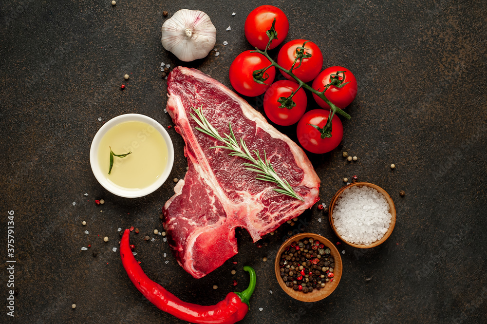 raw t-bone steak with ingredients on stone background 