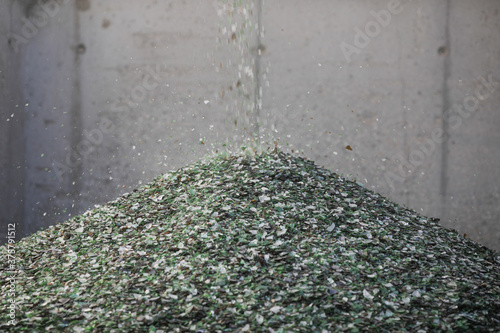 Details with shards of glass falling from a conveyor belt on a pile in a glass recycling facility. photo