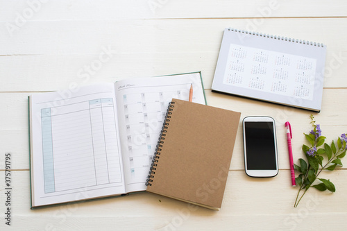 notebook account planner ,calendar and mobile phone for business work arrangement flat lay style on background white at office 