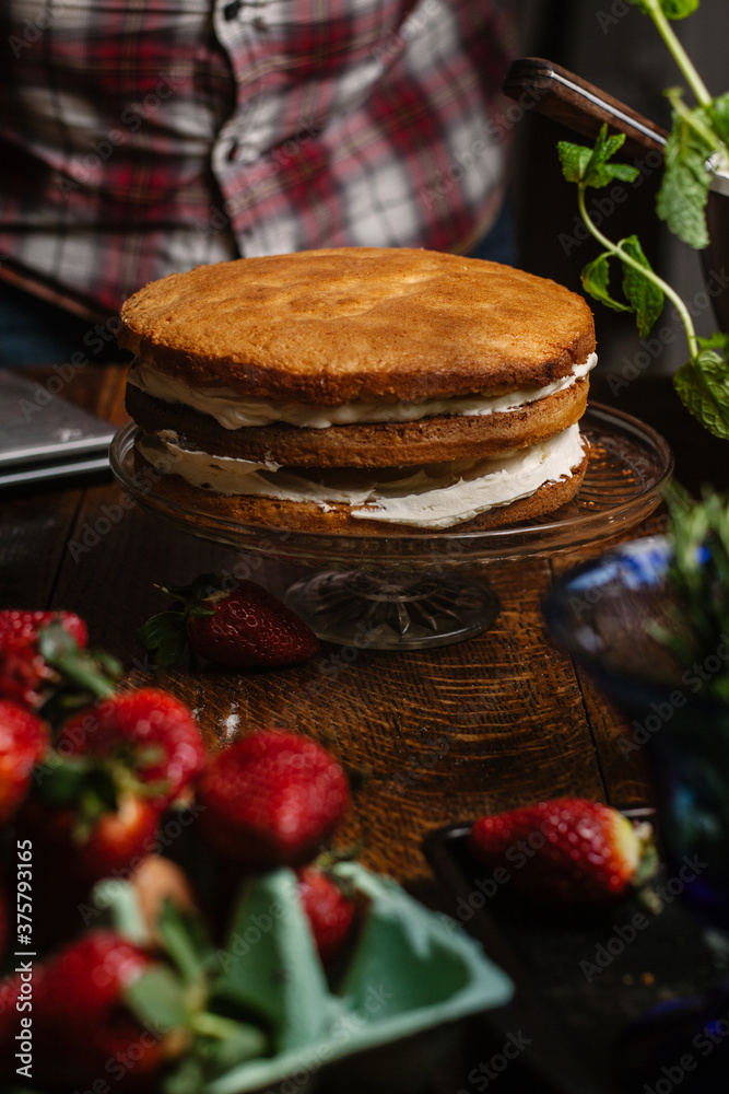 Three layer genoise sponge with cream in the process of being dressed. Three layer genoise sponge with cream in the process of being dressed.