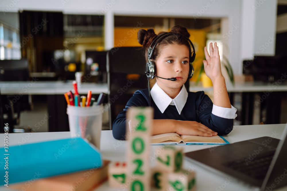 Fototapeta premium Online remote learning. Distance education. The girl raises her hand to answer the teacher's question. Covid-2019.