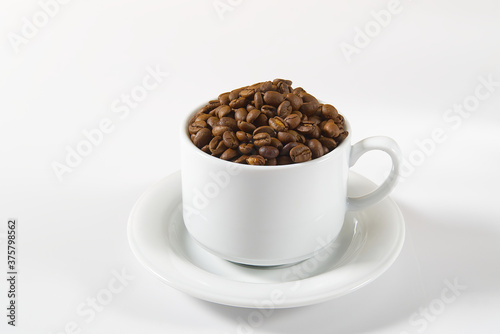 Coffee beans in white cup, close-up. White coffee cup with coffee seeds on white background. Concept For International day of coffee.