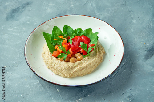 Classic hummus with vegetables and spinach in a white bowl