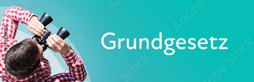 Grundgesetz. Mann bei Beobachtung mit Fernglas. Fokus auf Text/Wort. Panorama Format. Hintergrund blau/türkis. photo