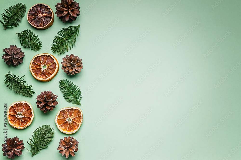 Christmas border of green fir branches, cones and dried oranges on a light green background. Christmas or New Years blank. Copy space