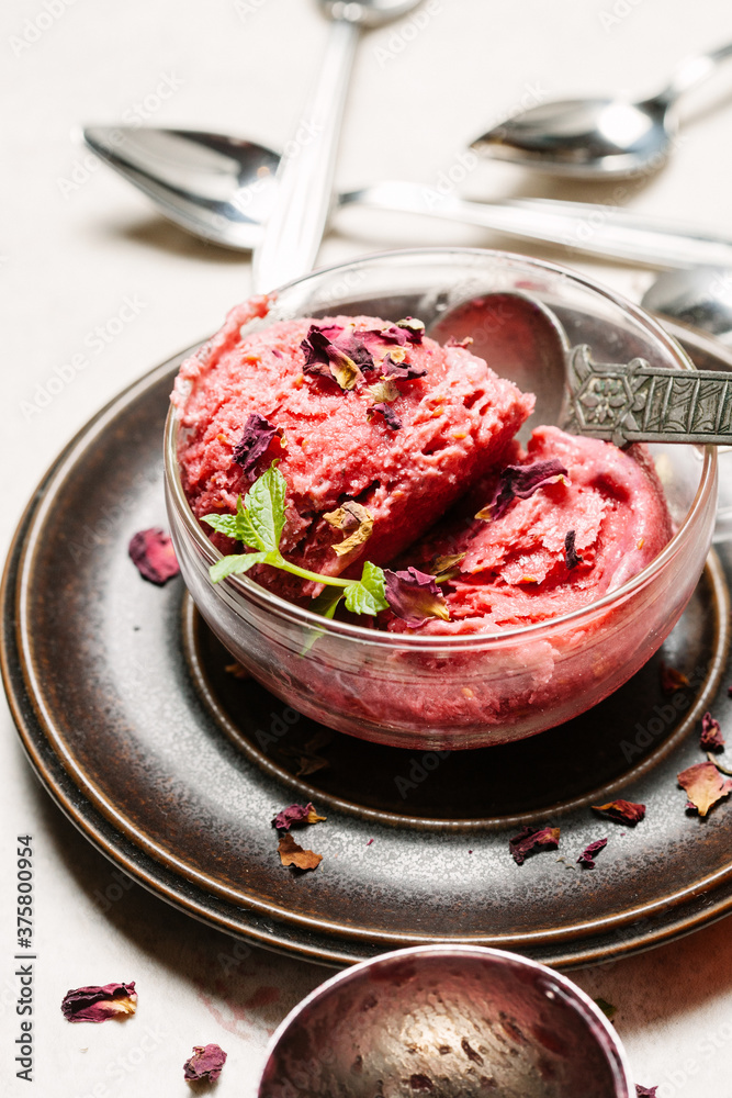 Raspberry and rose petal ice cream in glass bowl on table. Raspberry and rose petal ice cream in glass bowl on table.