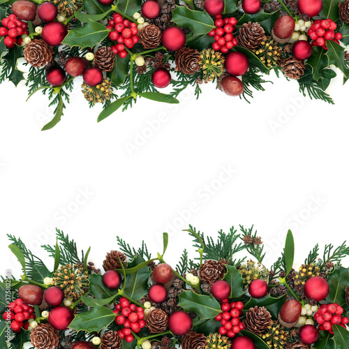 Christmas border with red bauble decorations, holly, mistletoe, ivy, acorns & cedar cypress on white background. Xmas & New Year festive composition. Flat lay, top view, copy space.