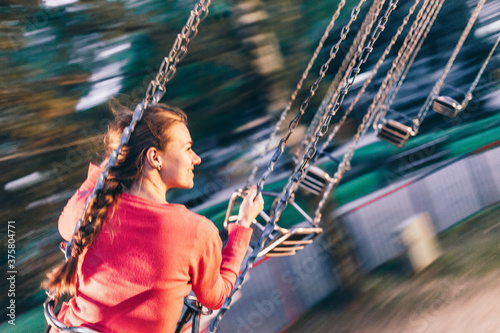 Young woman riding on a swing carousel in amusement park smiling photo