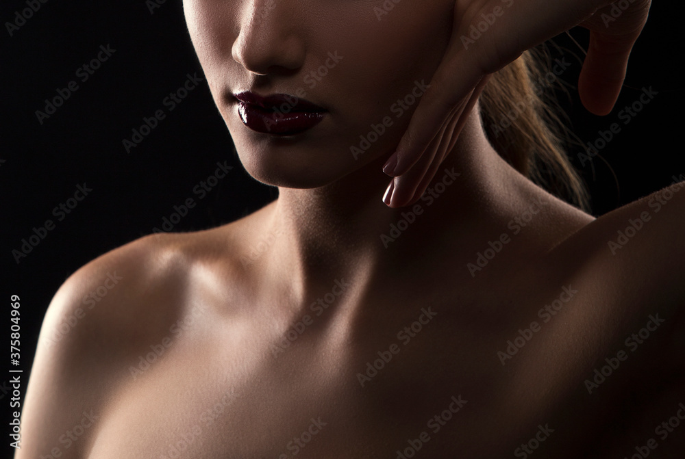Lips, hand, shoulders, partial beauty portrait of a young woman with healthy skin. Dark background Lips, hand, shoulders, partial beauty portrait of a young woman with healthy skin. Dark background