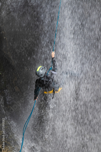 Person doing canyoning sport on Vanatarile Ponorului waterfall in Transylvania, Romania photo