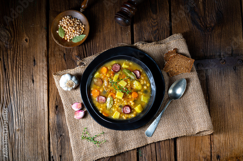 Rustic pea soup with bacon and sausages photo