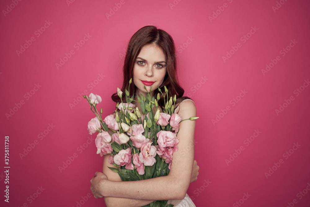 beautiful woman with a bouquet of flowers on a pink background in a light dress makeup model