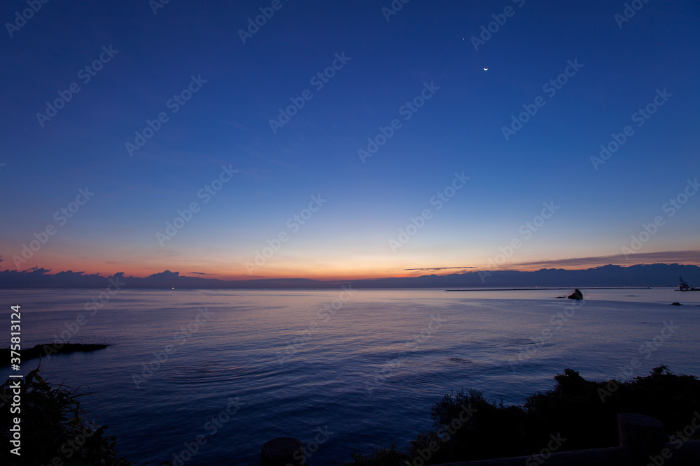 Fototapeta premium 夜明けの大海原と淡い光の星と月