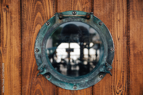 Old porthole in the wooden wall of a ship