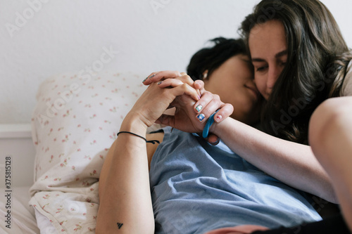 Loving lesbian couple holding hands in bed
