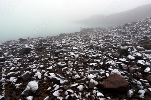 Alpine lake with rocky shores and emerald water. Morning frosts. Alpine lake Giybashkel (3240 meters above sea level), Caucasus. 