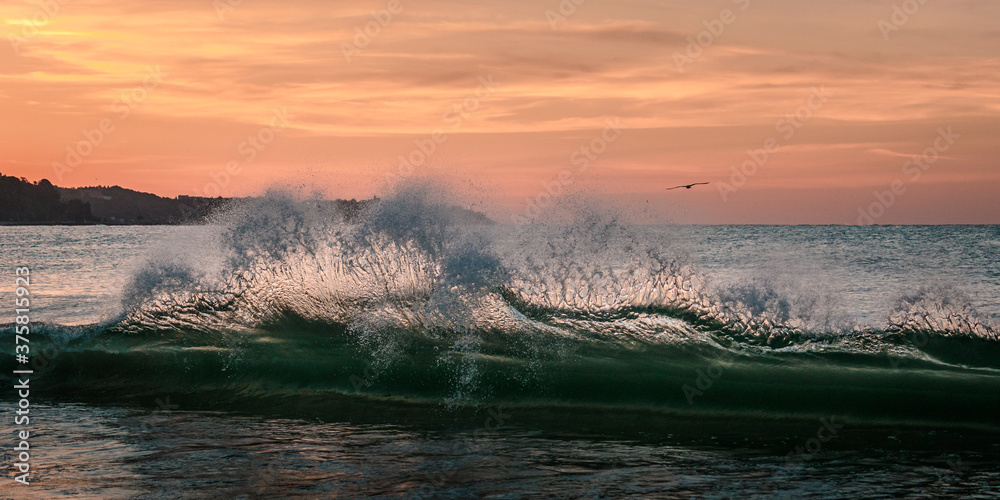 motion freeze of a crashing wave at sunrise or sunset