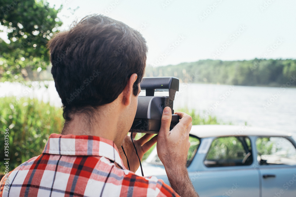 Portrait of Young Man Taking Polaroid Photo of Vintage Car Parked in Nature Portrait of Young Man Taking Polaroid Photo of Vintage Car Parked in Nature