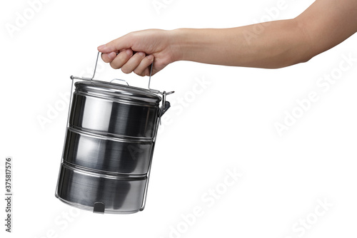 Hand holding tiffin carrier stainless steel lunch box isolated on white background with clipping path photo