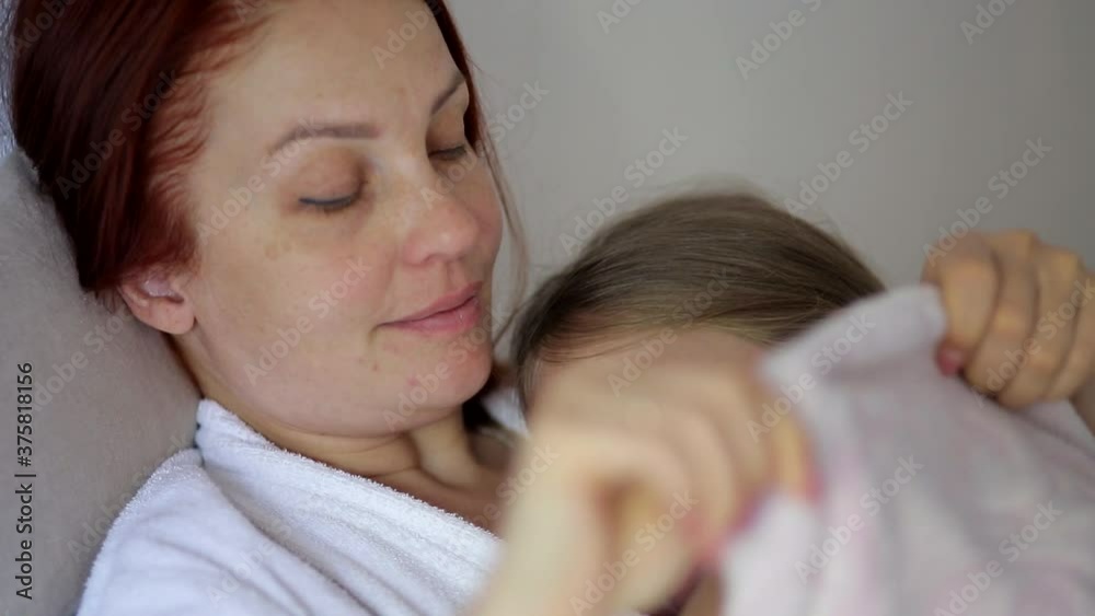 mother gently kisses and strokes the head of her daughter lying on the bed, motherhood and childhood mother gently kisses and strokes the head of her daughter lying on the bed, motherhood and childhood