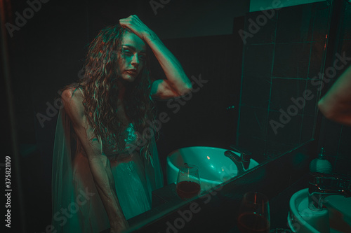 Obraz na płótnie mysterious woman wearing wedding dress looking at her scary reflection in a mirror. w salonie