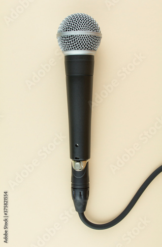 Professional vocal microphone with cable on beige background.