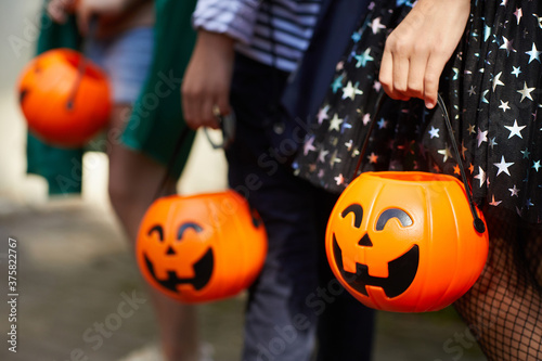 Close-up of children with pumpkins bags playing trick or treat outdoors photo