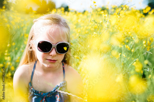A little girl in a wildflower meadow wearing shades