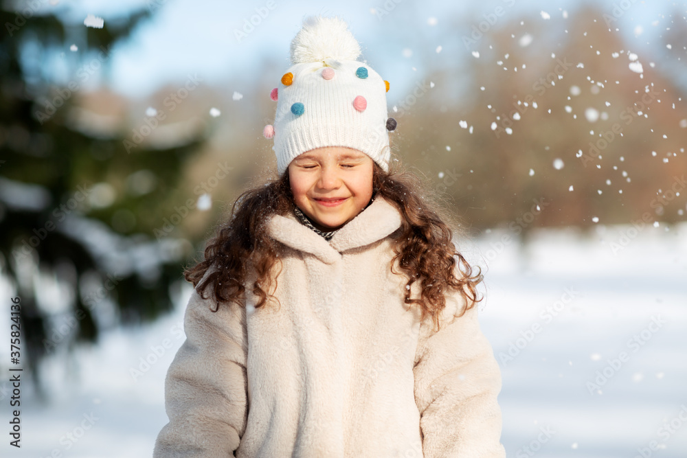 Obraz premium childhood, leisure and season concept - portrait of happy little girl in winter clothes outdoors