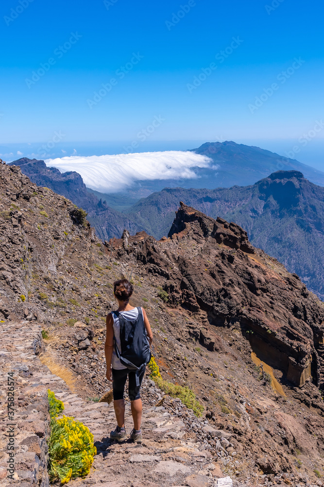 A young woman walking along the path of the Roque de los Muchachos at the top of the Caldera de Taburiente, La Palma, Canary Islands. Spain
