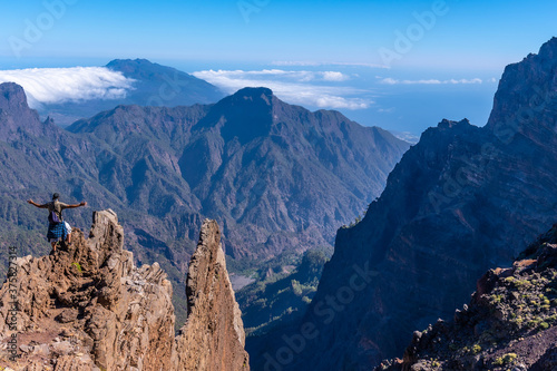 A young man after finishing the trek at the top of the volcano of Caldera de Taburiente near Roque de los Muchachos looking at the incredible landscape, La Palma, Canary Islands. Spain