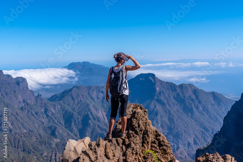 Fotografie A young woman looking out from the top of the Caldera de Taburiente volcano near Roque de los Muchachos one summer afternoon, La Palma, Canary Islands