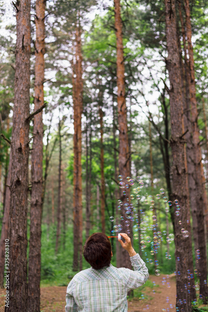 Woman blowing soap bubbles in a pine forest Woman blowing soap bubbles in a pine forest