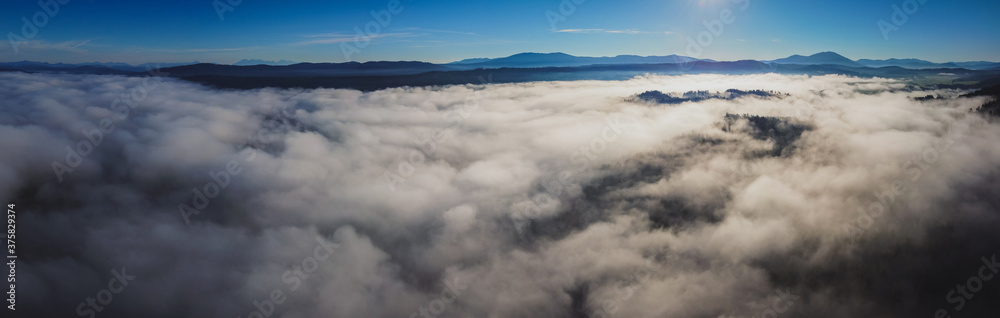 Early morning drone panorama of Planinsko Polje field in Slovenia during thick fog over the plain, with only higher hills such as Slivnica are seen sticking out.