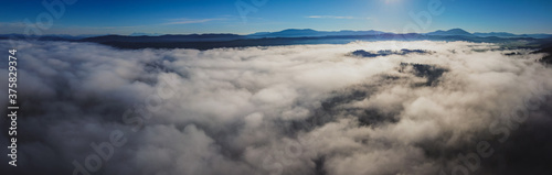 Early morning drone panorama of Planinsko Polje field in Slovenia during thick fog over the plain, with only higher hills such as Slivnica are seen sticking out.
