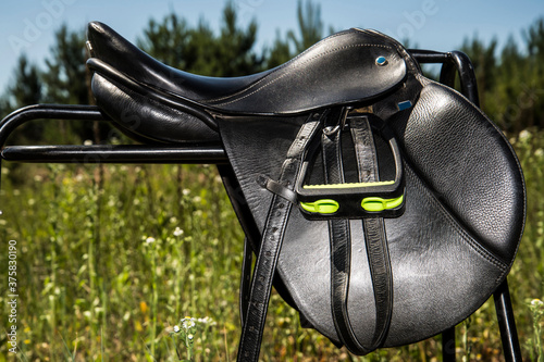 Black leather saddle for horse on a supporting fixture. photo