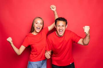 Happy couple won emotionally celebrating win on colored red background