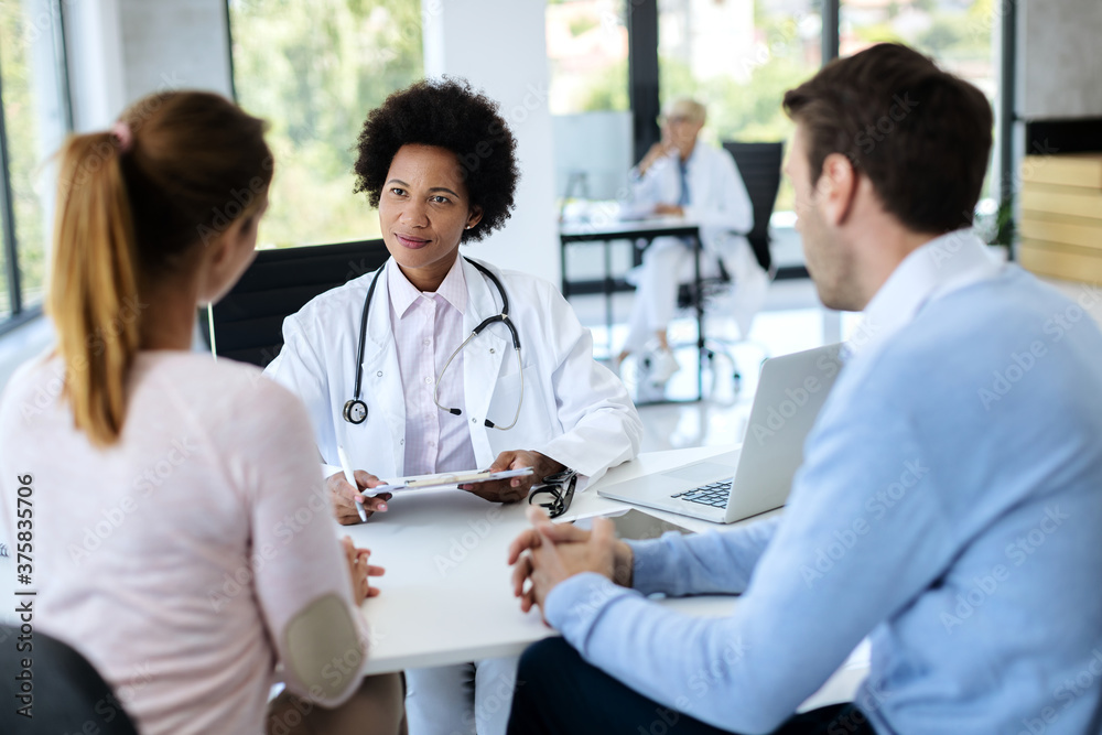 Smiling African American doctor having medical appointment with a couple at clinic. Smiling African American doctor having medical appointment with a couple at clinic.