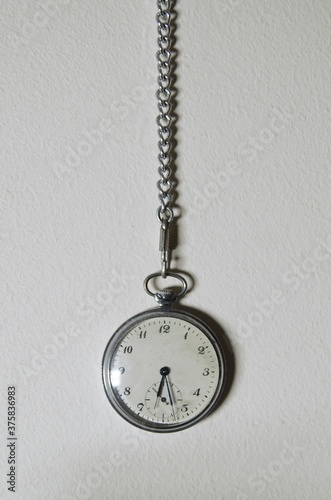 Old pocket watch hanging on the white wall