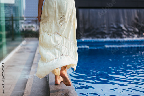 Beautiful woman walking on the edge of the pool