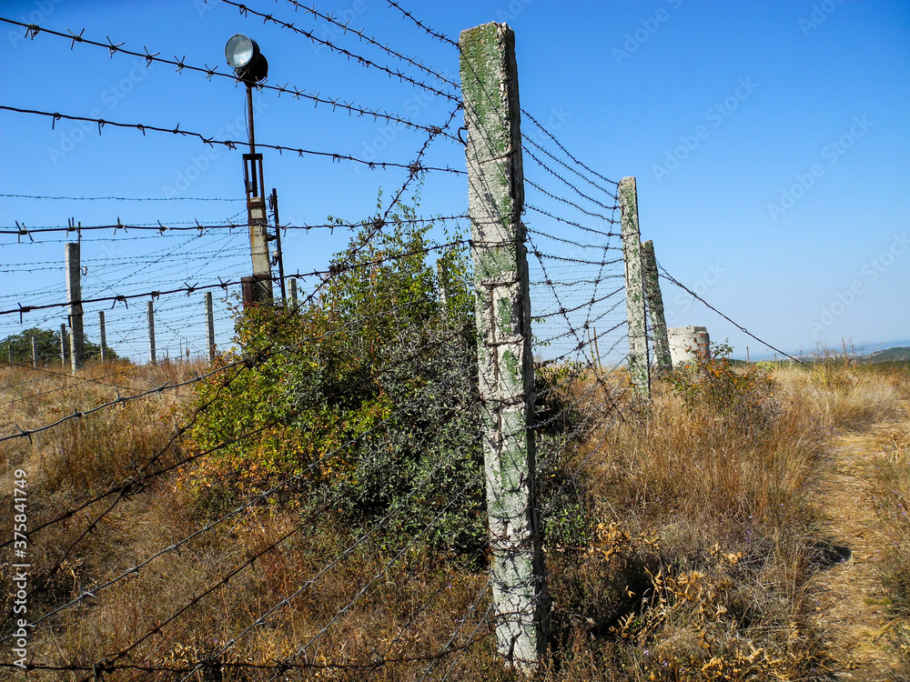 Fototapeta premium Pillars with barbed wire and spotlight 