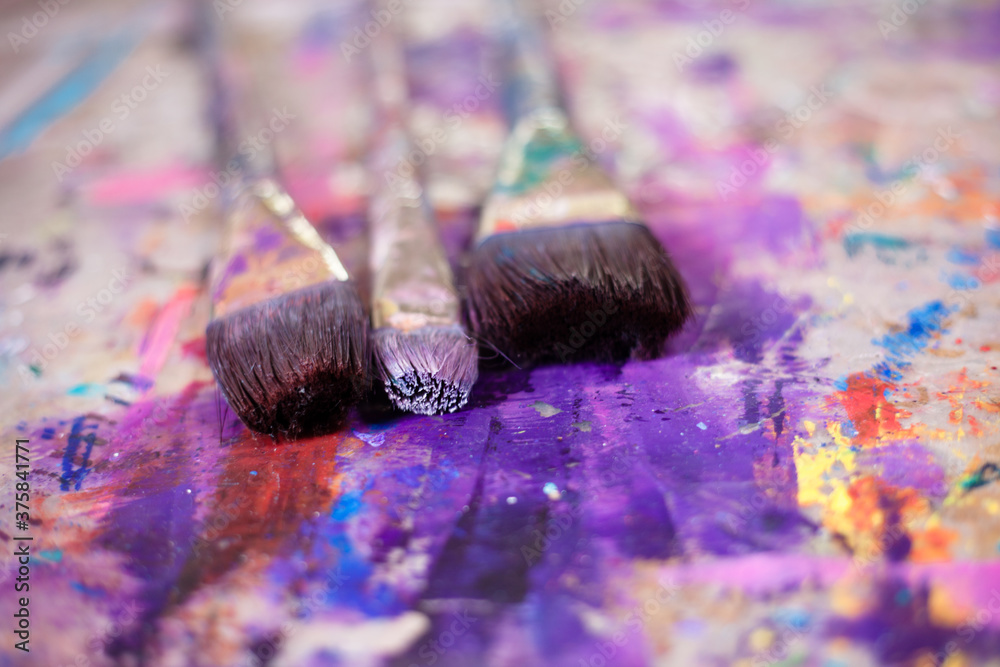 Used paint brushes stained with all colors in an art studio Used paint brushes stained with all colors in an art studio