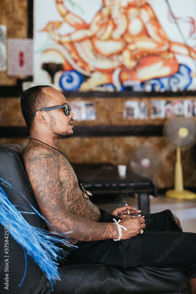 Thai tattoo artist smoking a cigarette during a break