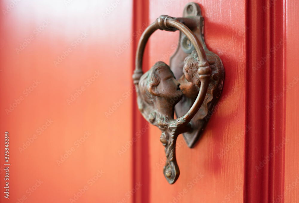 Door knocker on a red door with two people kissing Door knocker on a red door with two people kissing