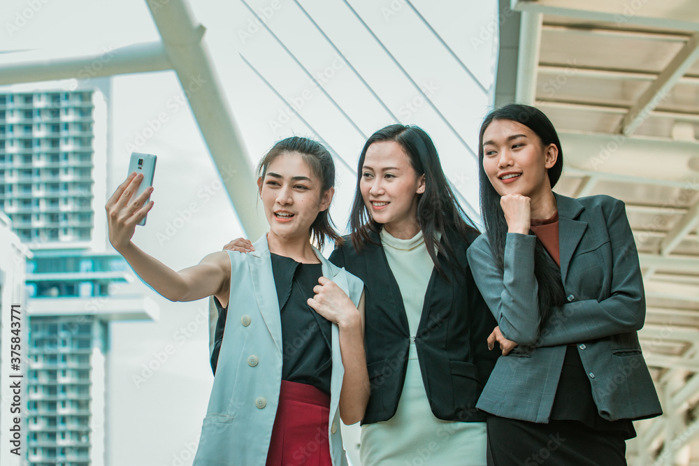 Obraz premium Businesswoman friends selfie with smartphone and pointing at screen surprised